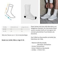 Ein Paar umweltfreundliche Unisex-Crew-Socken in Weiß mit schwarzer Spitze und Knöchelteil und einem kleinen Logo und Text im Retro-Stil "Beach Bum". Die Socken haben ein sportliches Design und eine bequeme Passform mit gepolstertem Fußbett. Die verwendeten Materialien sind umweltverträglich und fördern einen bewussten Konsum. Die Socken sind sowohl für Männer als auch für Frauen geeignet und können bei verschiedenen Aktivitäten getragen werden.