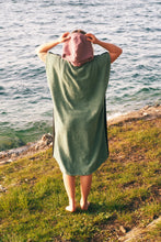 Eine Person, die einen bunten Boho Hippie Surf-Poncho mit aztekischem Muster trägt, steht an einem Strand. Der Poncho reicht bis knapp über die Knie und scheint aus einem dicken, saugfähigen Material zu bestehen. Bohemian Tribal Ethnic Patterned Colorful Beachwear Surfing Hooded Poncho Oversized Unisex Hippie-chic Festival fashion Beach accessory Mexican-inspired Southwestern Geometric Vibrant Multicolored Soft cotton Beach towel Quick-drying surfumkleide