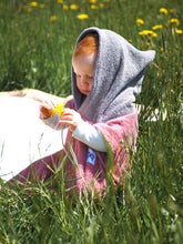 Ein Baby sitzt am Strand und trägt einen farbenfrohen Surfponcho mit einem aztekisch inspirierten Boho-Muster. Der Poncho besteht aus einem weichen, saugfähigen Material, das das Baby nach dem Schwimmen warm und trocken hält. Das lebendige und mehrfarbige Muster weist ethnische Details auf, die ihm ein Hippie-Chic-Feeling verleihen. Der Surfponcho hat eine Kapuze, um den Kopf des Babys vor Wind zu schützen, sodass er bis zu den Knien des Babys vollständig bedeckt ist. Boho hippie aztek