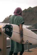 Eine Person, die einen bunten Boho Hippie Surf-Poncho mit aztekischem Muster trägt, steht an einem Strand. Der Poncho reicht bis knapp über die Knie und scheint aus einem dicken, saugfähigen Material zu bestehen. Bohemian Tribal Ethnic Patterned Colorful Beachwear Surfing Hooded Poncho Oversized Unisex Hippie-chic Festival fashion Beach accessory Mexican-inspired Southwestern Geometric Vibrant Multicolored Soft cotton Beach towel Quick-drying surfumkleide