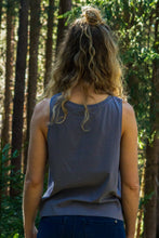 A gray high-neck tank top for women made from eco-friendly materials. The sleeveless top has a loose fit and reaches mid-hip. The fabric has a soft texture and a slight stretch that gives the wearer a comfortable feel. The product is sustainably produced and promotes conscious consumption.